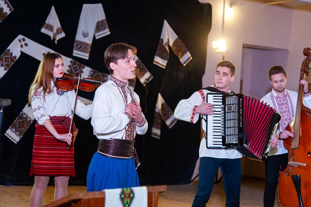 Звучить укр. нар. пісня в опр. Ірини Вілінської «Вечір надворі». Виконує Олег Нищота у супроводі студентського інструментального ансамблю «Троїсті музики»